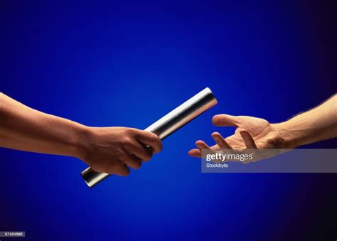 Closeup Of The Handover Of A Baton From A Relay Race High Res Stock