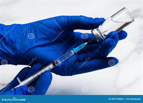 Hands In Surgical Gloves Preparing Medical Syringe And Needle For