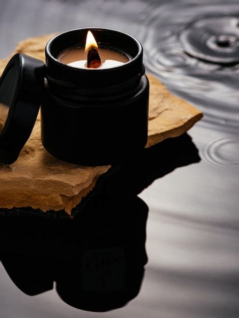 Premium Photo A Candle In A Black Jar Stands On A Stone In The Water