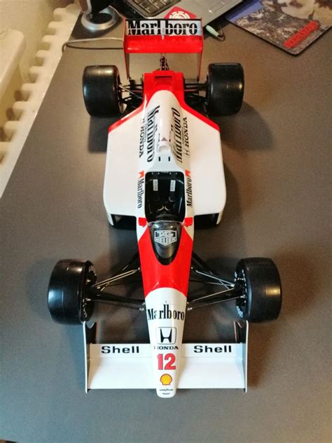 A Red And White Race Car On Display In A Room With Gray Carpeted Flooring