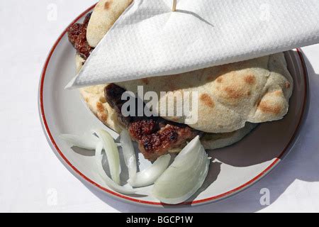 Cevapcici in bread with sliced onion served on a plate. Bosnia, Bosnian ...