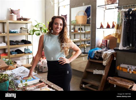 Female Assistant In Clothes Shop Standing With Hand On Hip Stock Photo