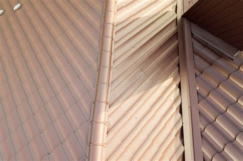 Detail View Of House Rooftop Covered With Brown Metal Tile Sheets Stock