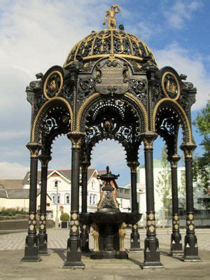 An Ornate Black And Gold Gazebo With A Fountain