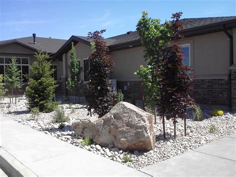 A Large Rock Sitting In Front Of A House Next To Some Bushes And Rocks