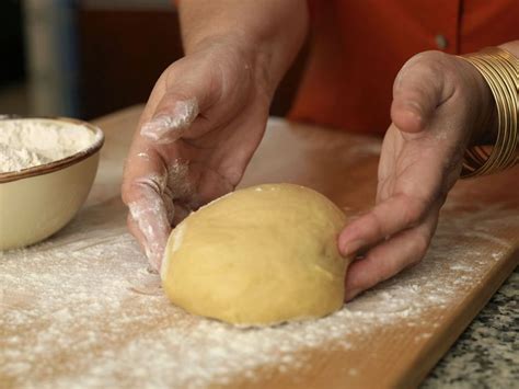 A Person Kneading Dough On Top Of A Wooden Table