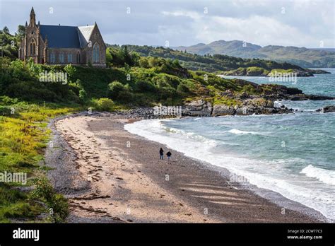 Couple walking on beach with Gairloch Free Church on headland beyond ...