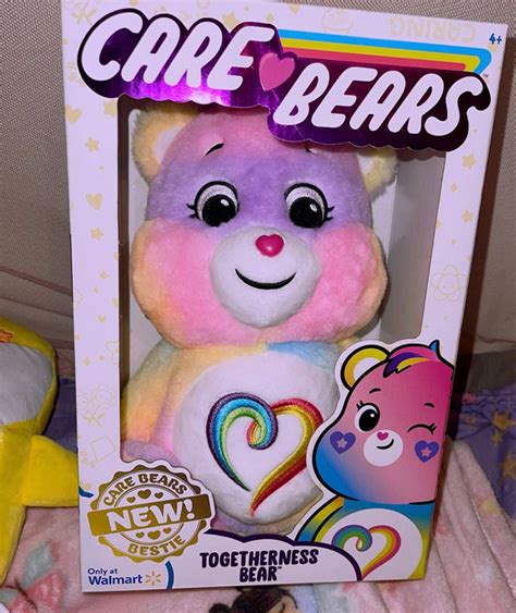 A Pink And Purple Teddy Bear In A White Box With The Word Care Bears On It