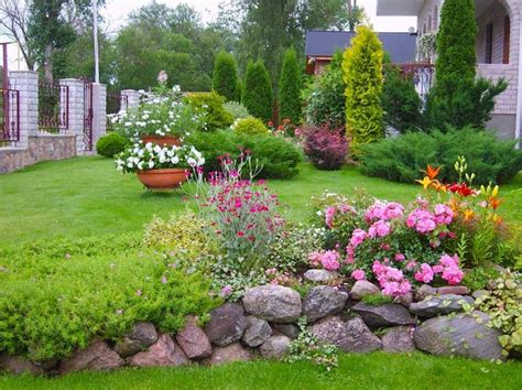 a garden filled with lots of flowers next to a lush green lawn and ...