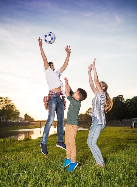 Niños felices saltando y jugando con pelota al aire libre día soleado