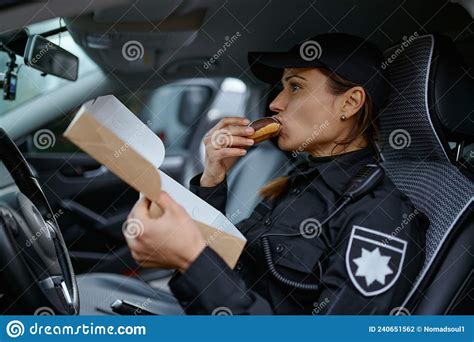 Une Femme Policier En Train De Manger Des Beignes Dans La Voiture Photo