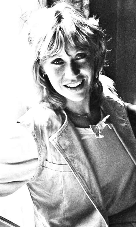 A Black And White Photo Of A Woman Sitting In A Chair Smiling At The Camera