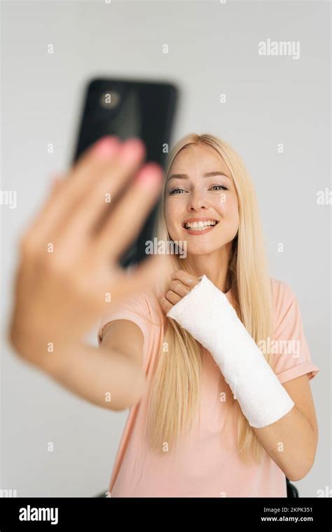 Vertical Portrait Of Positive Young Blonde Woman With Broken Arm