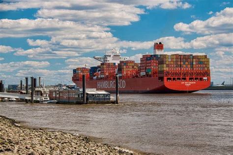 A Large Cargo Ship In The Water With Other Boats Around It And Clouds