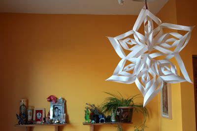 A White Paper Snowflake Hanging From The Ceiling In A Room With Yellow