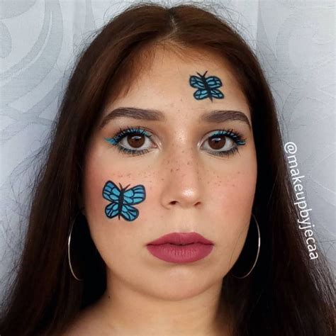 A Woman With Blue Butterflies Painted On Her Face And Eyebrows Looking