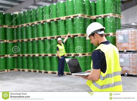 Worker In A Warehouse With Oil Barrels Checks The Stock Stock Photo