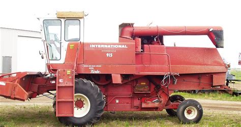 A Large Red Tractor Parked On Top Of A Grass Covered Field