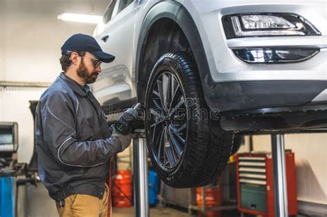 Mechanic With A Clipboard Inspecting Car Chassis Of A Lifted Car Using