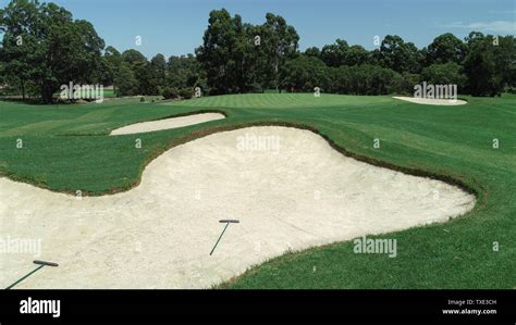 Golf Course Green With Red Flag Next To Sand Bunker Hazards With Rakes