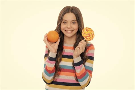 Chica adolescente feliz en suéter colorido con fruta naranja y paleta