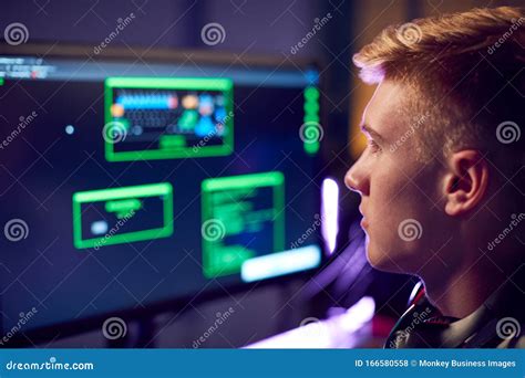 Male Teenage Hacker Sitting In Front Of Computer Screens Bypassing