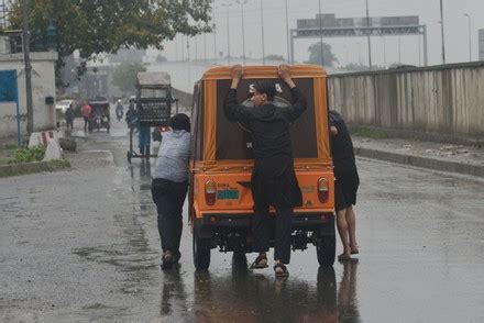 Pakistani Commuters Wade Through A Flooded Street At Baghban Pura Area