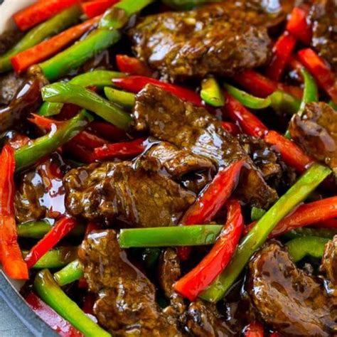 Beef Stir Fry With Red Peppers And Green Onions In A Skillet On A Table