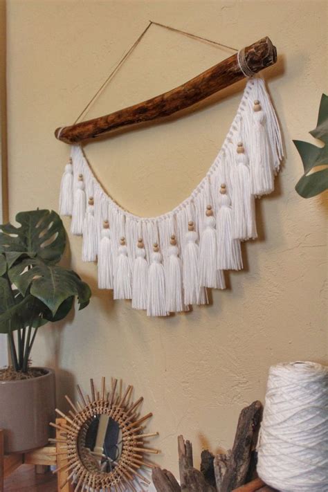 A Wall Hanging With White Tassels Next To A Potted Plant And Other Items