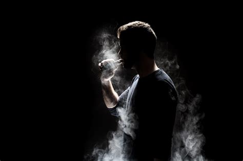 Premium Photo Man Smoking Electronic Cigarette Against Black Background