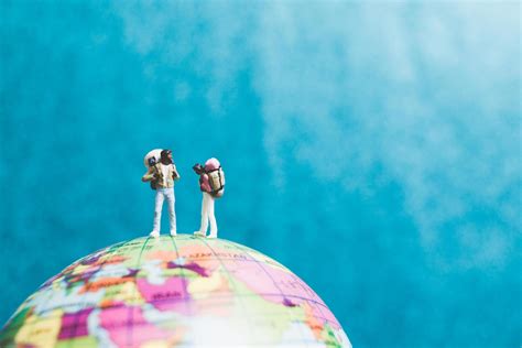 Miniature travelers with backpacks standing on a world globe and