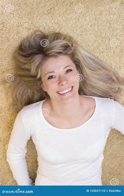 Portrait De Femme Se Trouvant Sur Le Plancher Et Le Sourire Photo Stock