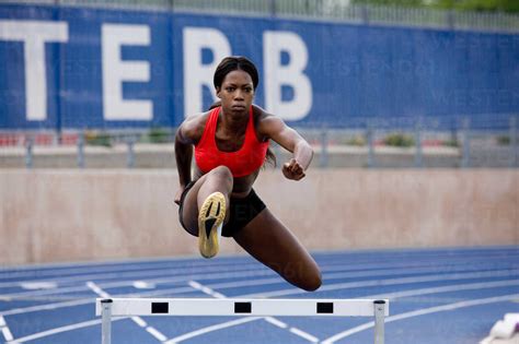 Runner Jumping Over Hurdles On Track Stock Photo