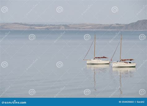 Two Very Similar Sailing Boats On Calm Water With Reflection Serene