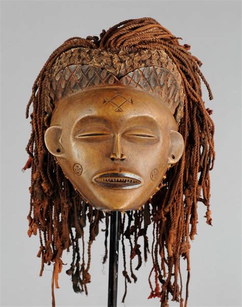 A Wooden Mask With Dreadlocks On Its Head