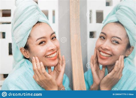 Attractive Asian Woman Standing In Front Of Mirror With Towel Stock