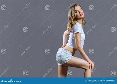 Blonde In Denim Shorts On Gray Studio Background Copy Space Stock