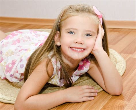 La Petite Fille De Sourire Se Trouve Sur Un Plancher De Maison Photo