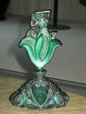 A Green Glass Vase Sitting On Top Of A Wooden Table Next To A Lamp Shade