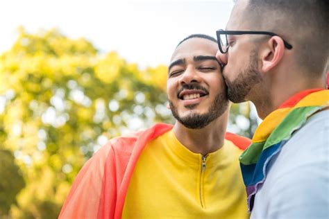 ストレットの虹色の旗を抱きしめて愛を示している若い同性愛者のカップルの肖像画。 Lgbtと愛の概念。 無料の写真