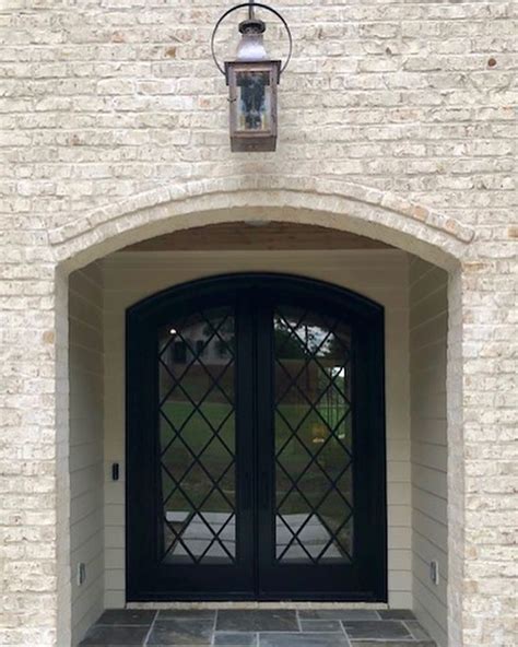 Modern French Front Door Featuring A Dark Double Arched Composite Wood Door With Privacy Glass