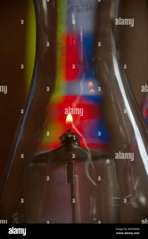 A Single Flame Burns Inside The Glass Globe Of An Oil Lamp With Stained Glass Forming A Colorful