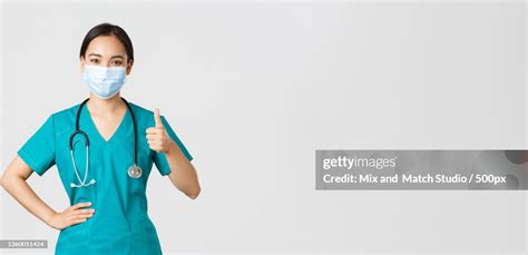 Portrait Of Female Doctor Wearing Surgical Mask Against White