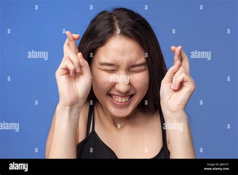 Asian Girl Crosses Her Fingers For Good Luck And Closes Her Eyes The