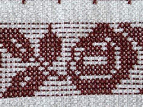 A Close Up View Of A Cross Stitch Pattern With Red And White Stitches On It