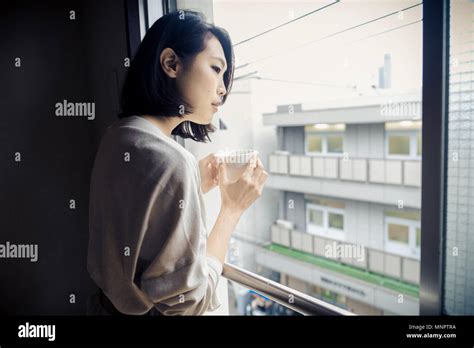 Japanese Woman Sitting In A Traditional Tokyo Apartment And Drinking A Cup Of Hot Tea Stock