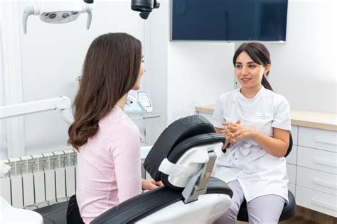 Female Dentist Talking To A Young Patient During Appointment In Modern