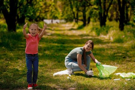 Fille blonde avec symbole écologique et sa mère ramassant des ordures dans le parc Photo Premium