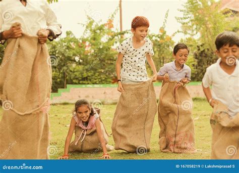 Children`s Playing Potato Sack Jumping Race At Park Outdoor Kids