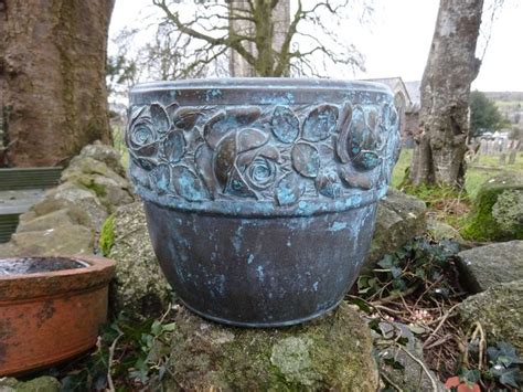 A Large Blue Planter Sitting On Top Of A Moss Covered Rock Next To A Tree